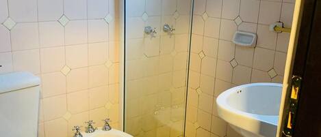 A bathroom with a toilet, bidet, and a glass-enclosed shower area.