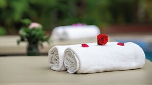 Two neatly rolled white towels with red rose petals on a beige surface, likely in a hotel setting. - Angkor Style Resort&Spa (Siem Reap)