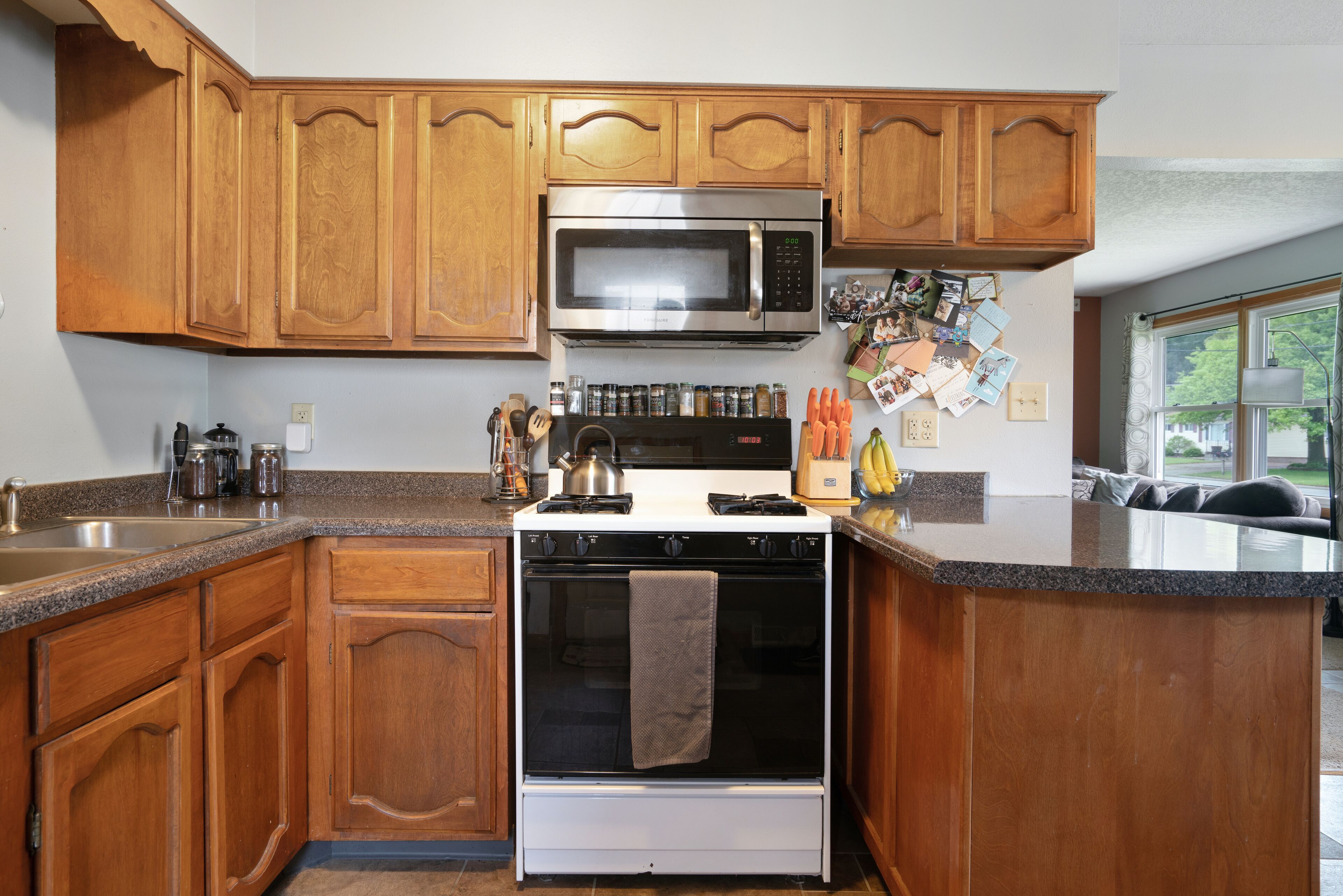 A kitchen with wooden cabinets, a stainless steel microwave, and a stove.