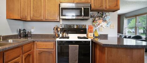 A kitchen with wooden cabinets, a stainless steel microwave, and a stove.