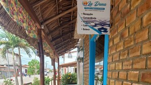 An outdoor seating area with tables and chairs, a covered roof, and a signboard listing amenities like reception, convenience, and café.