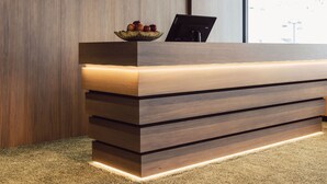 Un comptoir d’accueil avec un revêtement en bois, un saladier rempli de fruits et un ordinateur portable.