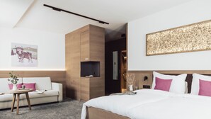Une chambre d’hôtel moderne avec un grand lit, un canapé, une petite table et une étagère fixée au mur.
