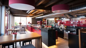 Un espace bar moderne avec un plafond en bois, des touches de rouge et un comptoir bien garni de bouteilles et de verres de toutes sortes.