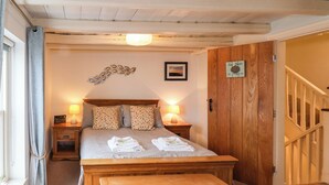 A bedroom with a wooden bed, bedside lamps, a wooden chest, and a wooden wardrobe. - Madelines View (Whitby)