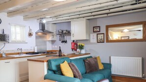 A compact kitchen with white cabinets, a central island, and a dining area with a table and chairs. - Madelines View (Whitby)