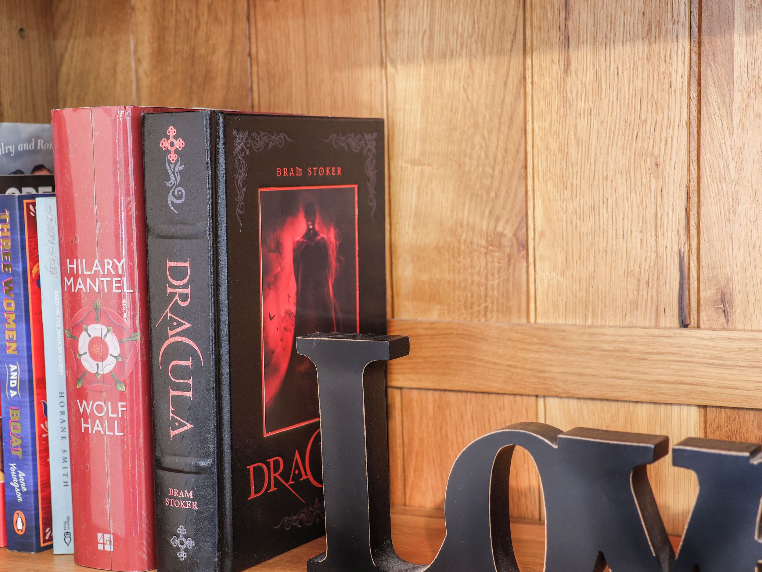 A bookshelf with books, including titles like 'Dracula' and 'Wolf Hall'.