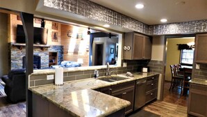 A modern kitchen with granite countertops, dark cabinetry, and a stone backsplash.
