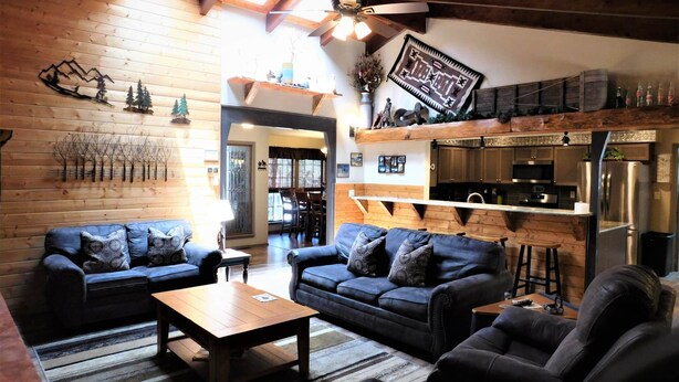 A cozy living room with two sofas, a coffee table, and a kitchen area with modern appliances.