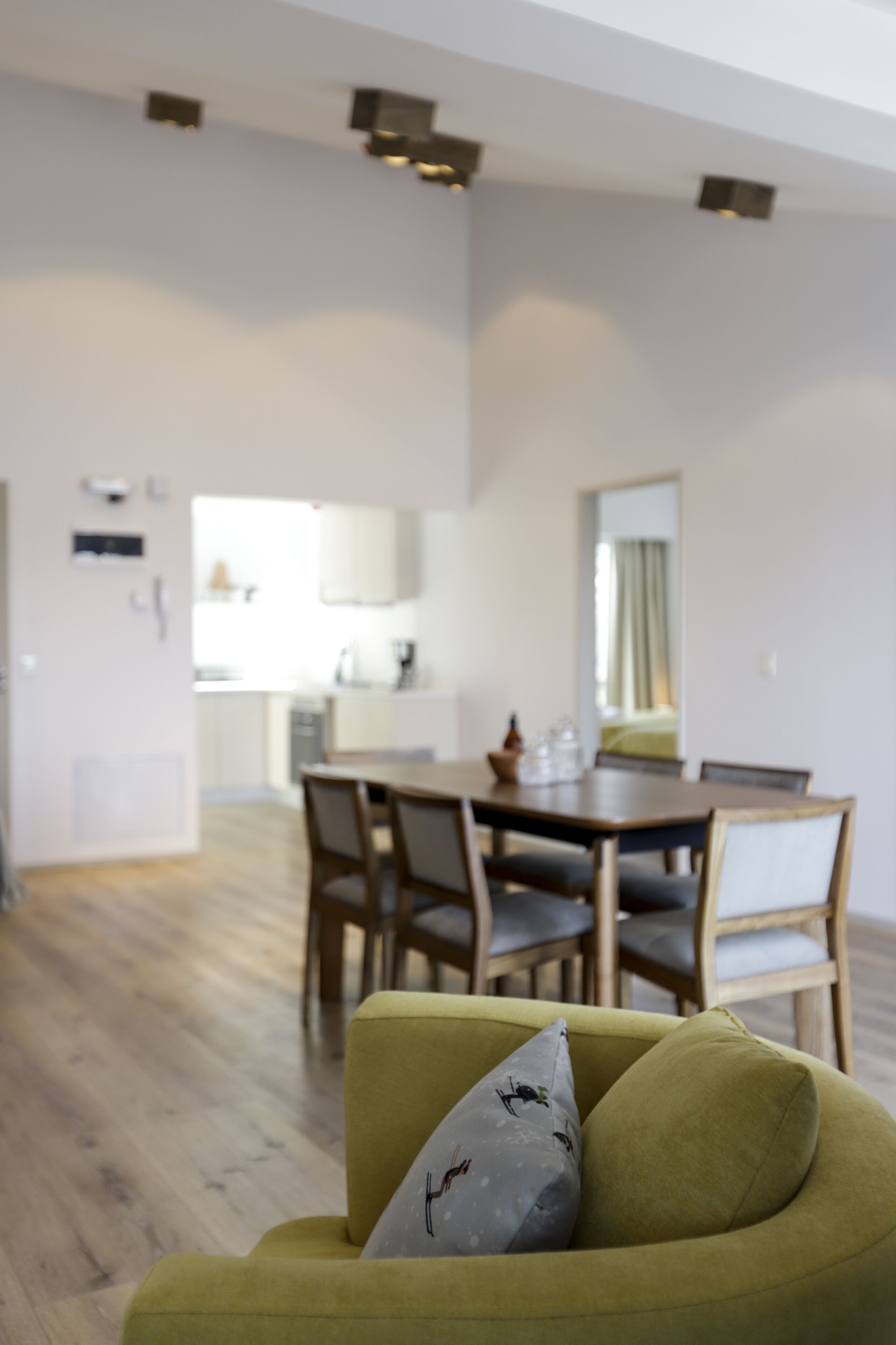 Una sala de estar moderna con un sofá verde, una mesa de comedor con sillas y una cocina al fondo.