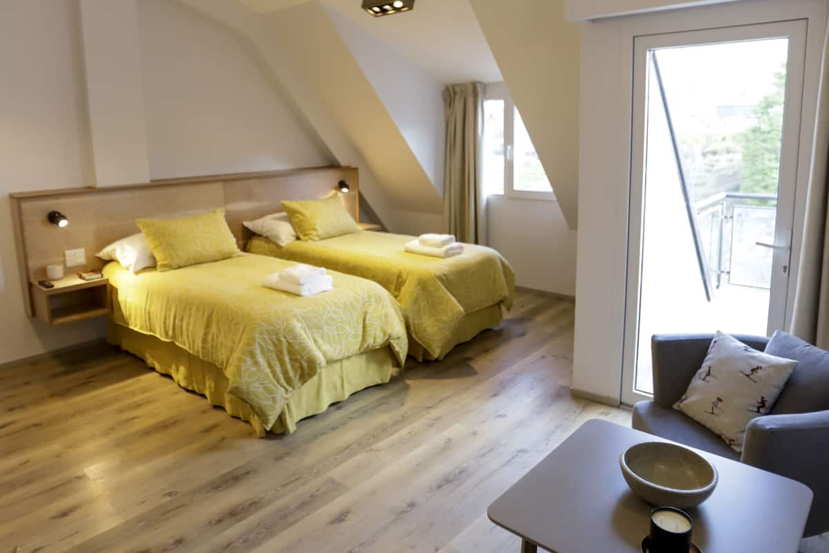 Ein Schlafzimmer mit zwei Betten, einem kleinen Tisch mit einer Schale und einer Tasse sowie einem Sofa.