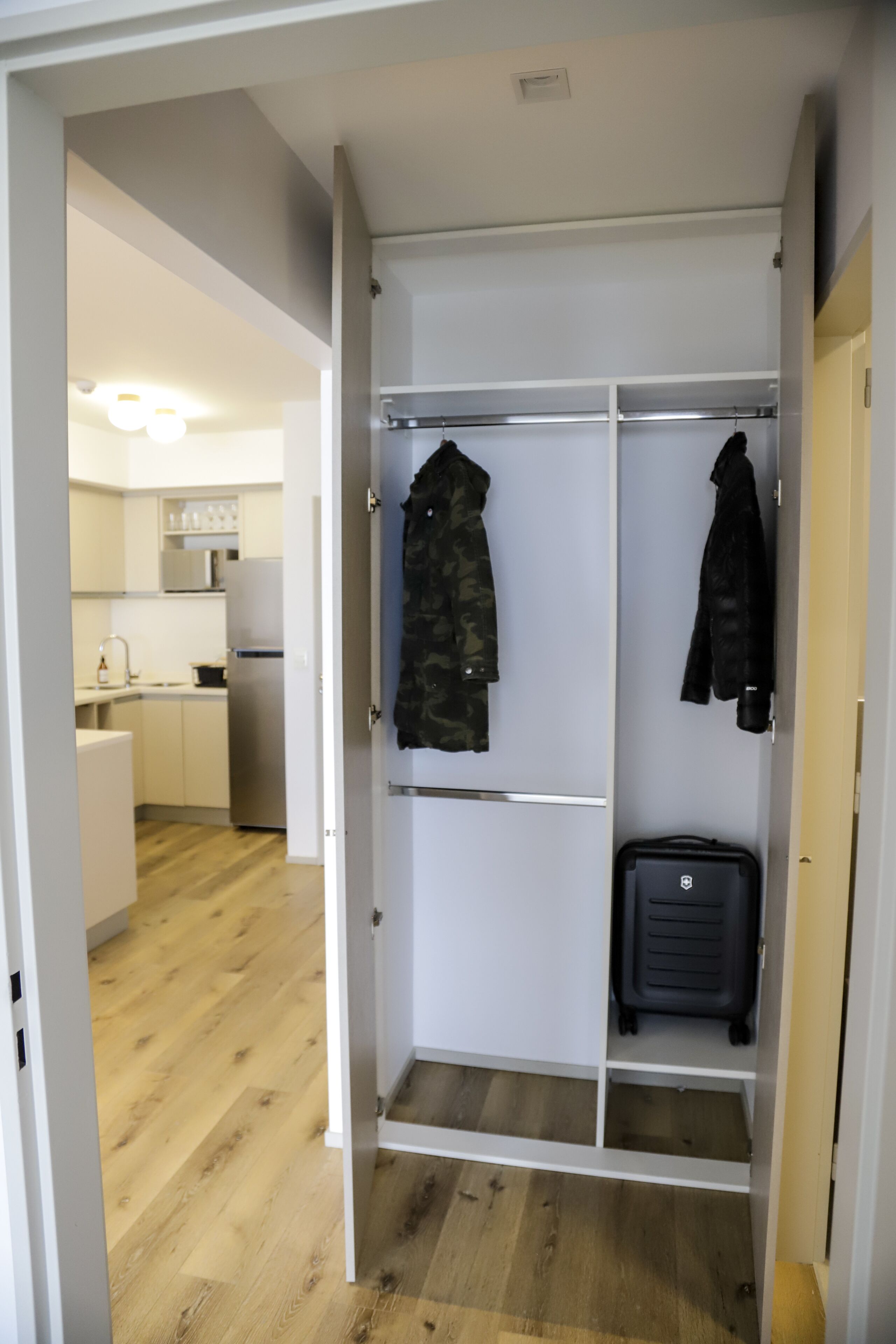 A walk-in closet with a mirrored wardrobe, a hanging rack, and a suitcase.