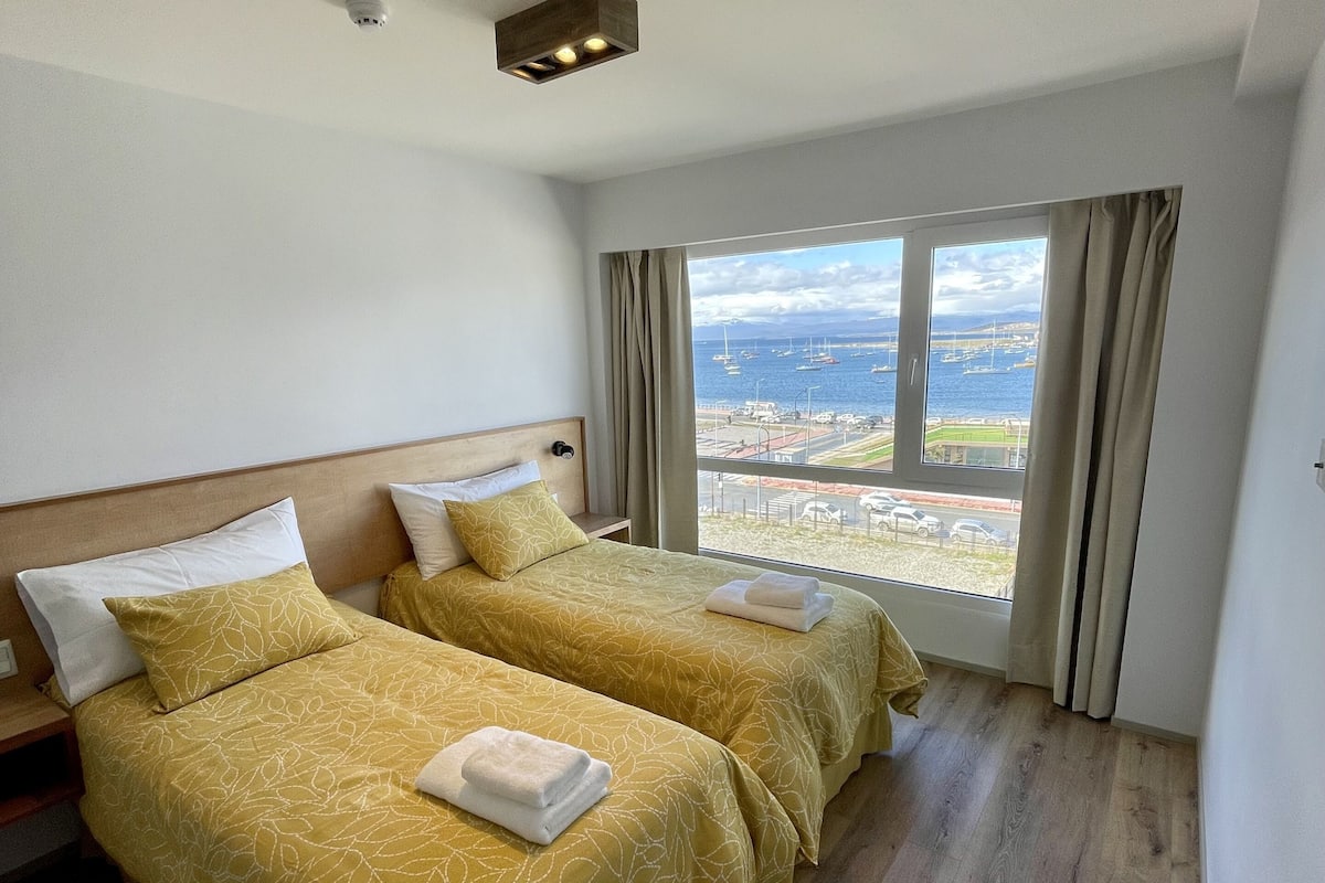 Ein Hotelzimmer mit zwei Betten, Meerblick und einer Deckenleuchte.