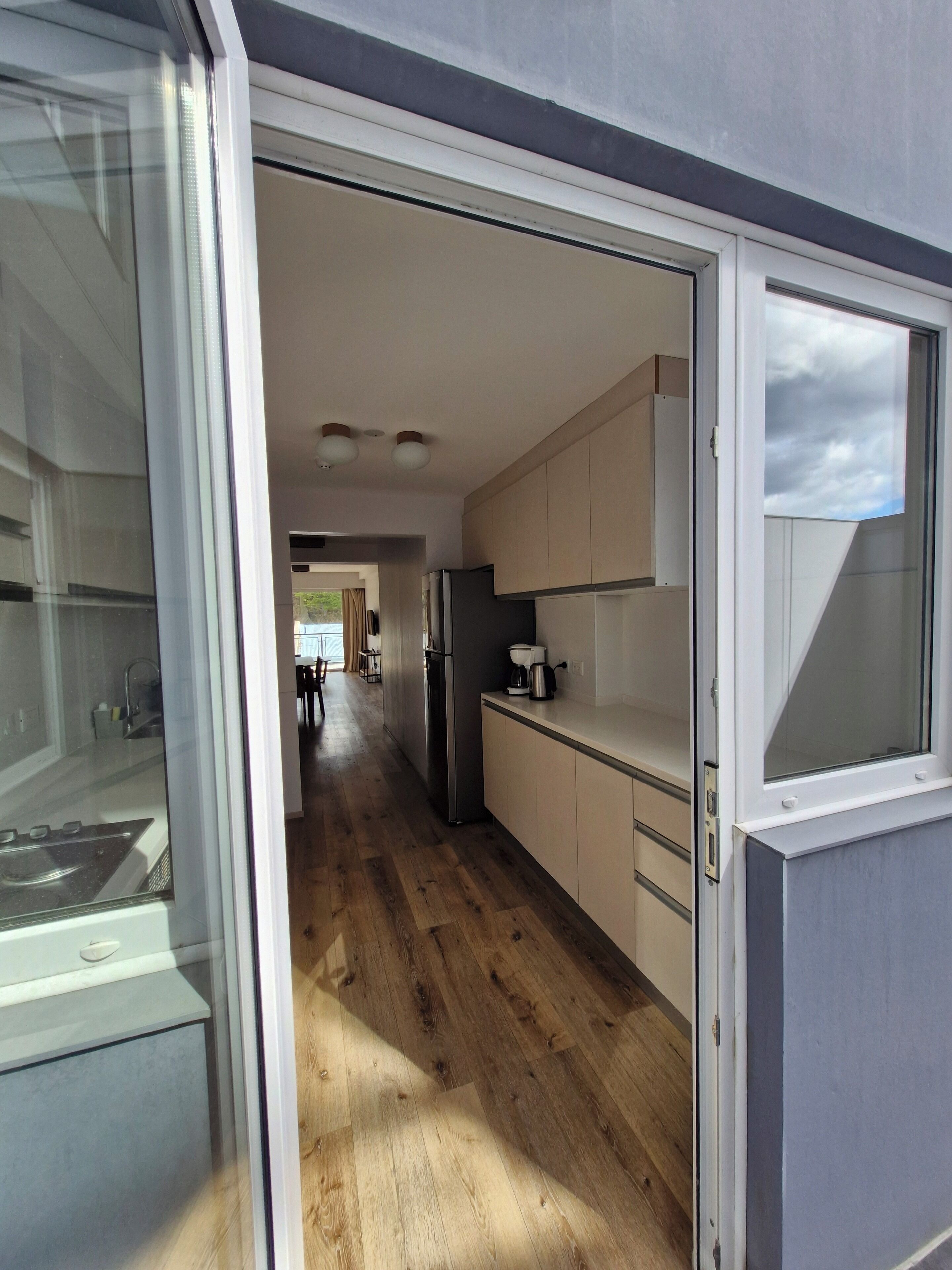 A modern kitchen with wooden flooring, white cabinets, and a built-in oven.
