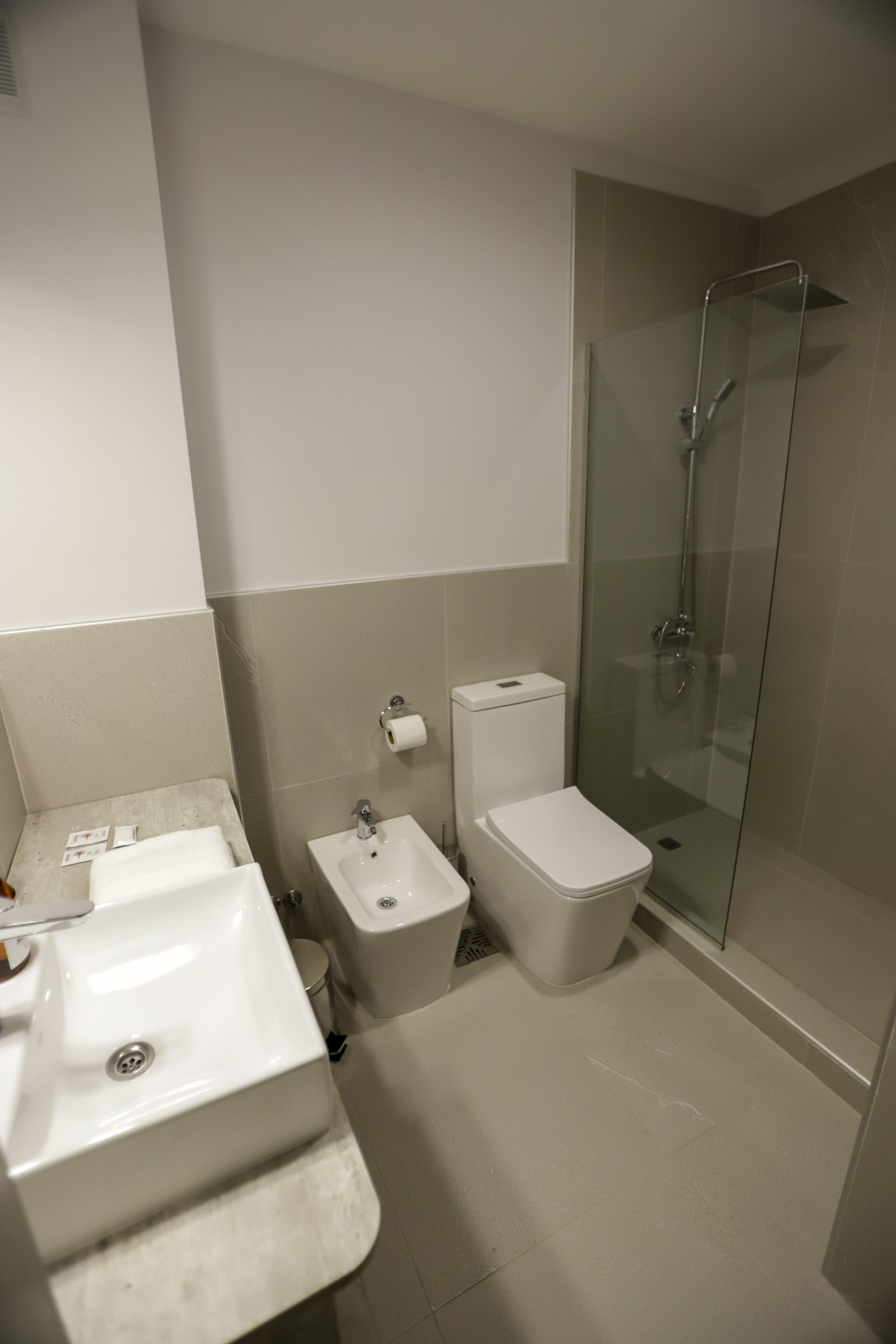 Ein Badezimmer mit Waschbecken, Toilette, Bidet und einer Duschkabine.
