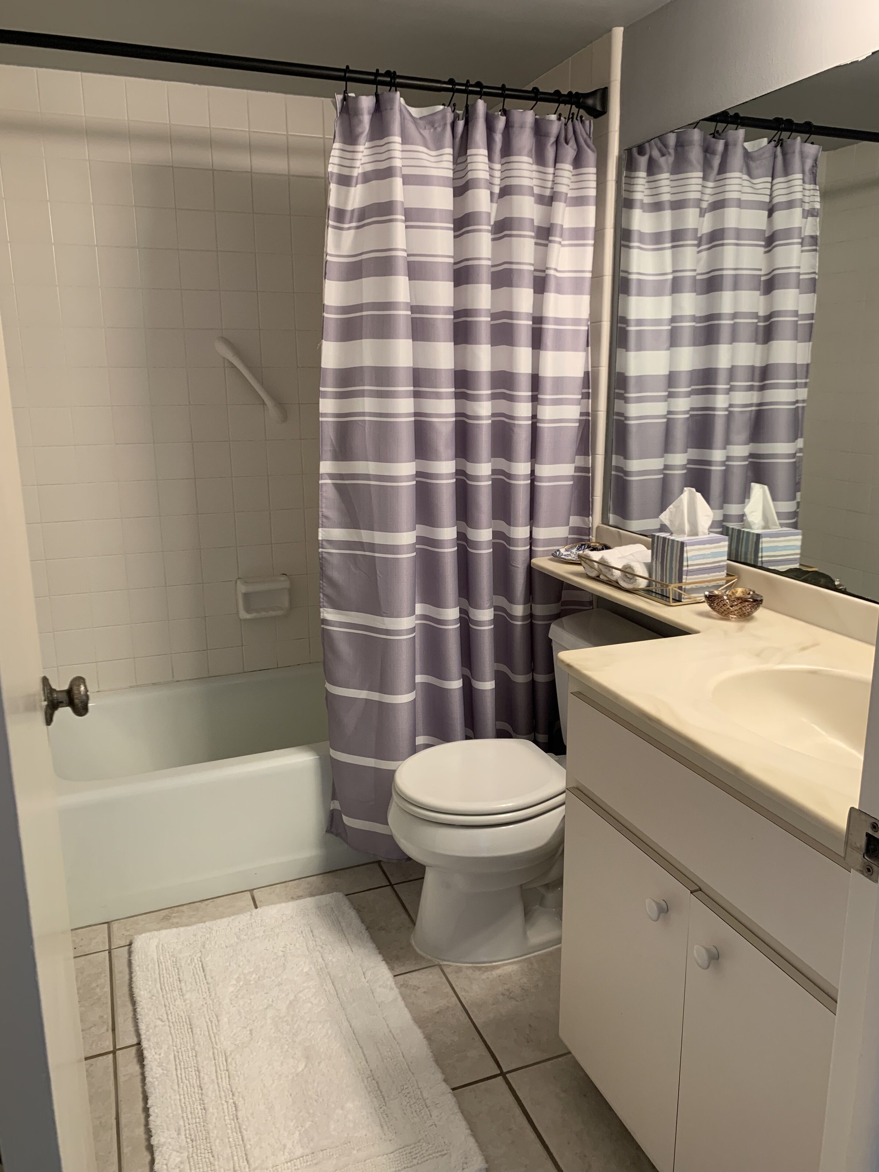 A bathroom with a bathtub, toilet, and a sink with a mirror.
