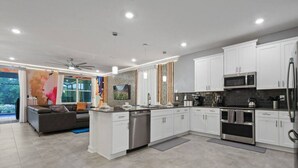 Une cuisine moderne avec des meubles blancs, des appareils en acier inoxydable et un îlot central.