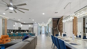 Une cuisine moderne avec des meubles blancs, un îlot central et des tabourets de bar bleus.