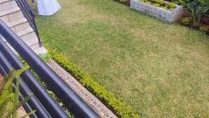 Un jardín cuidado con césped, macetas de piedra y un tendedero con ropa.