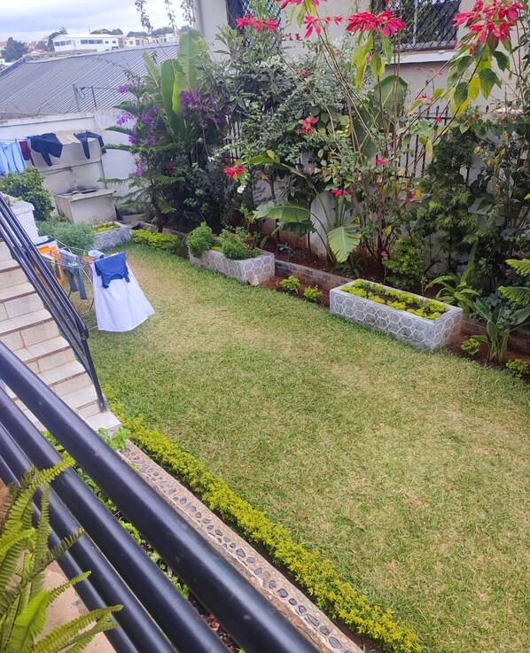 A well-maintained garden with a lawn, stone planters, and a clothesline with laundry. - Villa Saphira (Antananarivo)