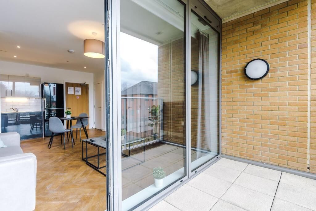 A modern apartment with a kitchen, dining area, and a balcony with a glass door.