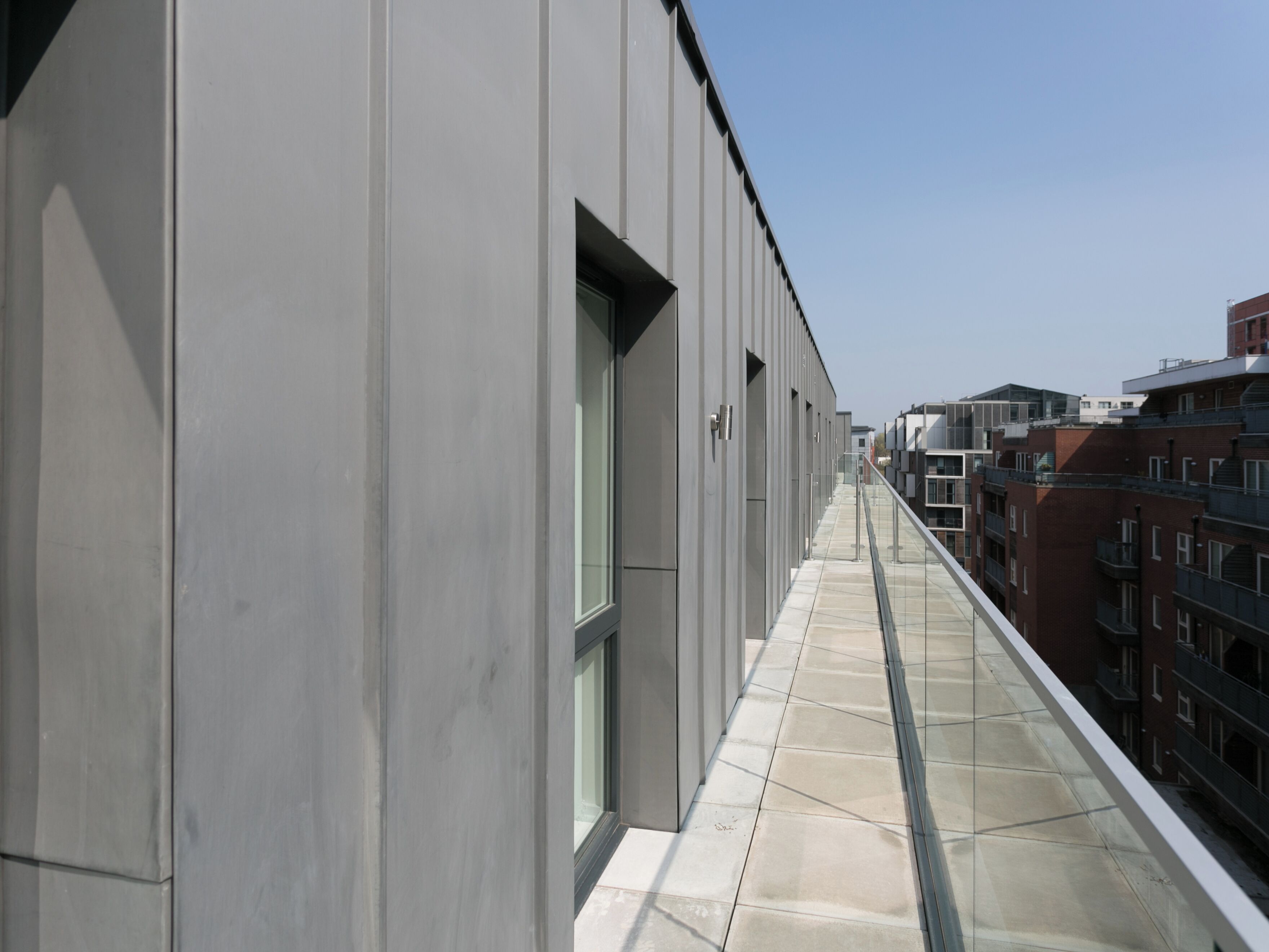 A modern building with a long, narrow corridor and a glass railing overlooking a cityscape.