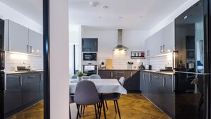 Une cuisine moderne avec des meubles de couleur sombre, un îlot central et un coin repas comprenant une table et des chaises.