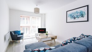 A modern living room with a sofa, a chair, a coffee table, and a TV displaying 'NETFLIX'.