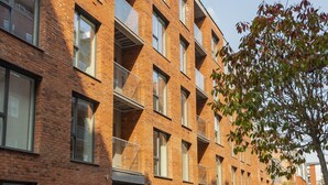 Un edificio in mattoni con diversi piani, balconi e ampie finestre.