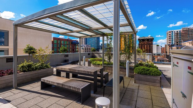 Una terraza en la azotea con mobiliario exterior, una pérgola y vistas a la ciudad.