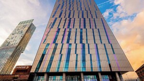 A modern high-rise building with a grid-like facade, likely a commercial or office building. - 1 Bedroom Apartment (Manchester)