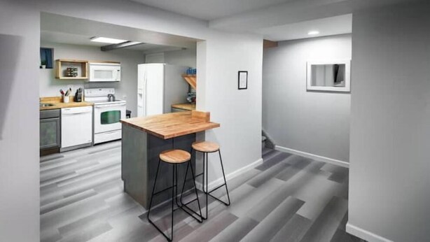 A modern kitchen with a wooden bar stool area, white appliances, and a grey herringbone floor. - Strawberry Peaks Ogden 6 guests (Ogden)