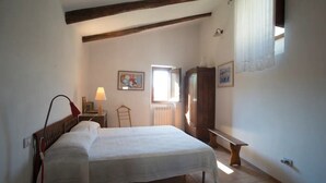 A bedroom with a bed, a nightstand, a lamp, a window, and a wardrobe. - Tuff farmhouse, terrace and garden, pets allowed (Latera)