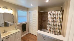 A bathroom with a sink, mirror, vanity, shower, and a window with blinds. - Farmhouse at the foot of the Blue Ridge Mountains (Waynesboro)