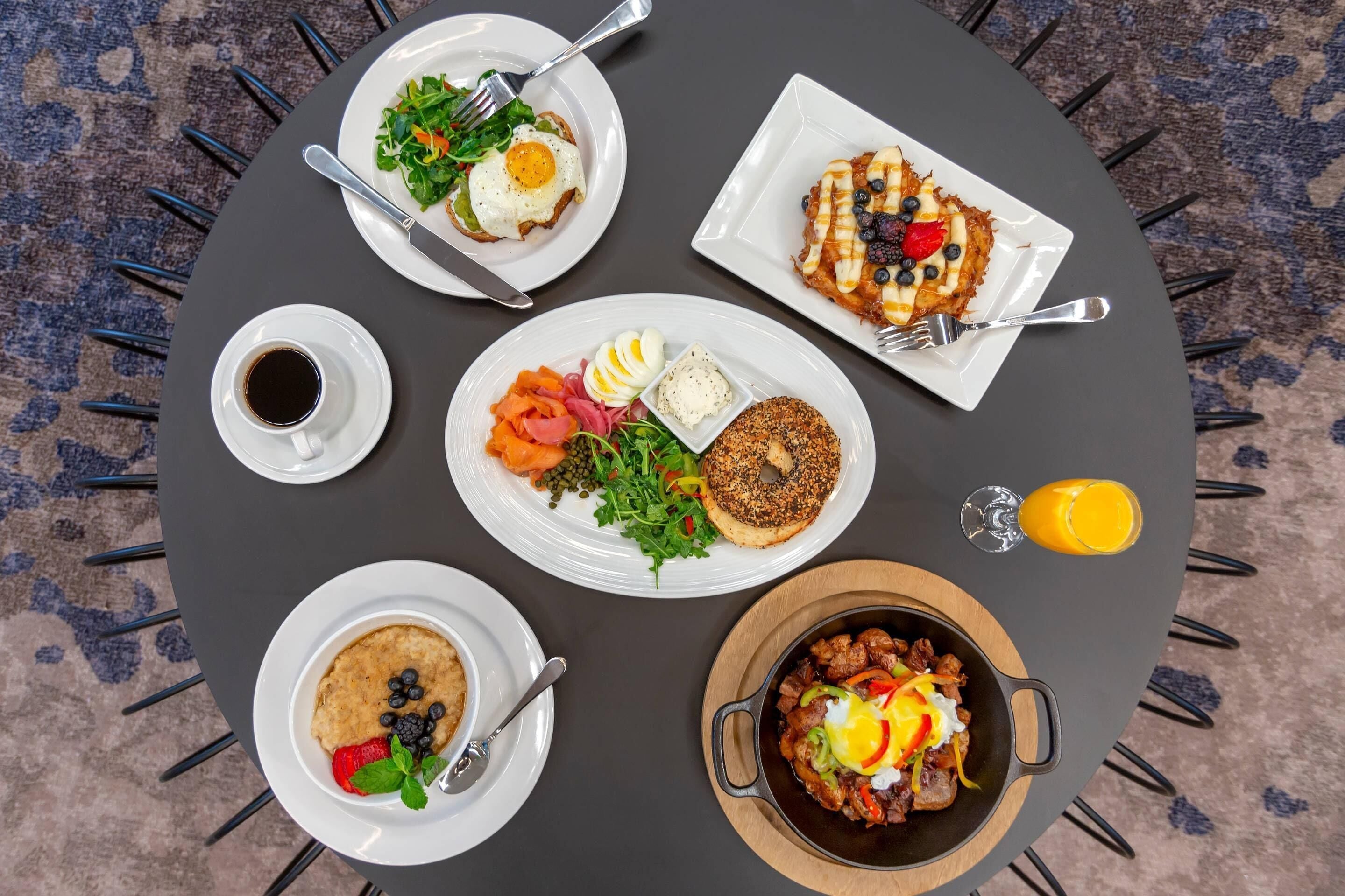 Une table ronde sur laquelle sont disposés divers plats pour le petit-déjeuner, notamment des œufs, des crêpes et un bol de soupe.