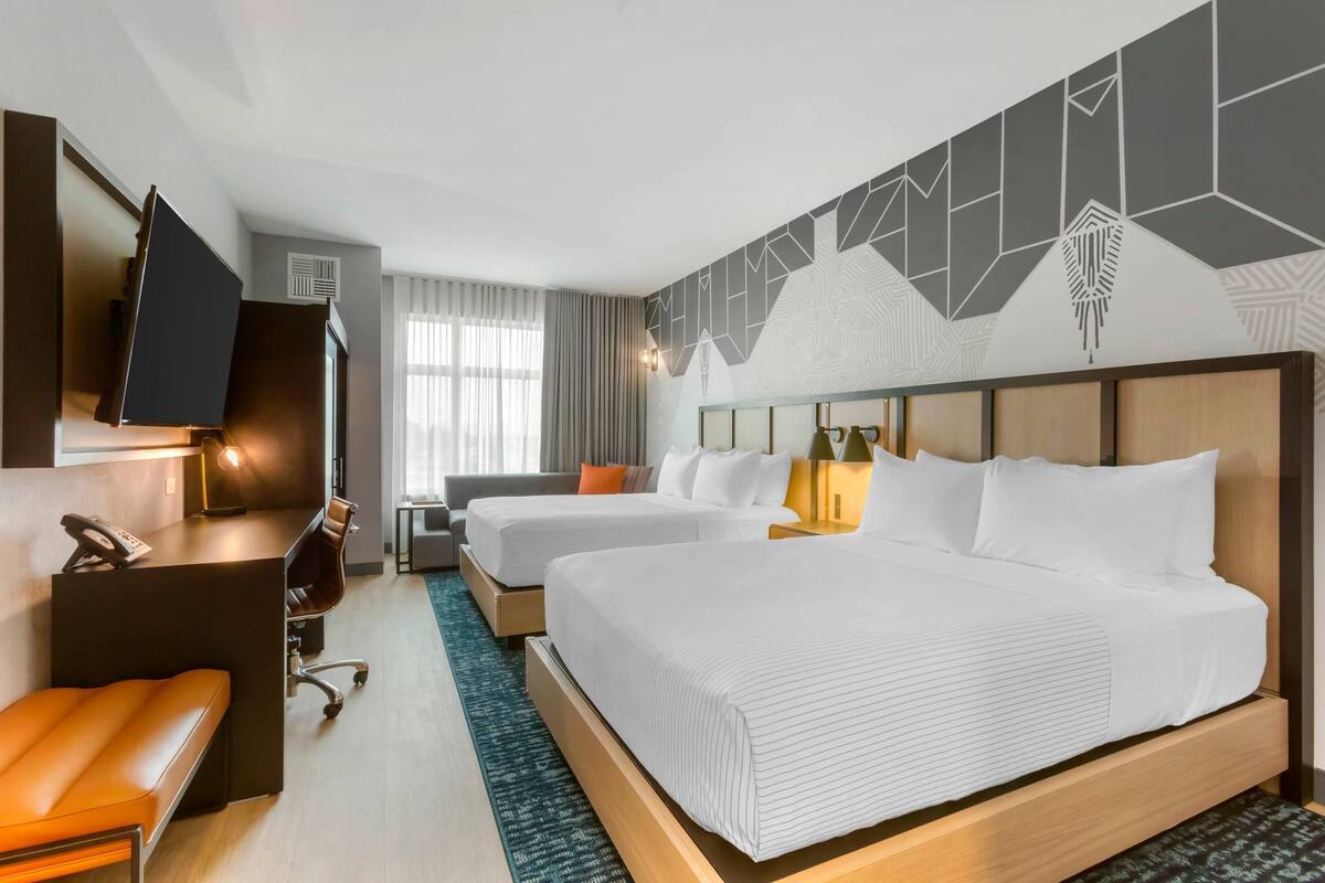 Ein Hotelzimmer mit einem großen Bett, einem Schreibtisch mit Stuhl, einem Fernseher und einer Sitzecke.