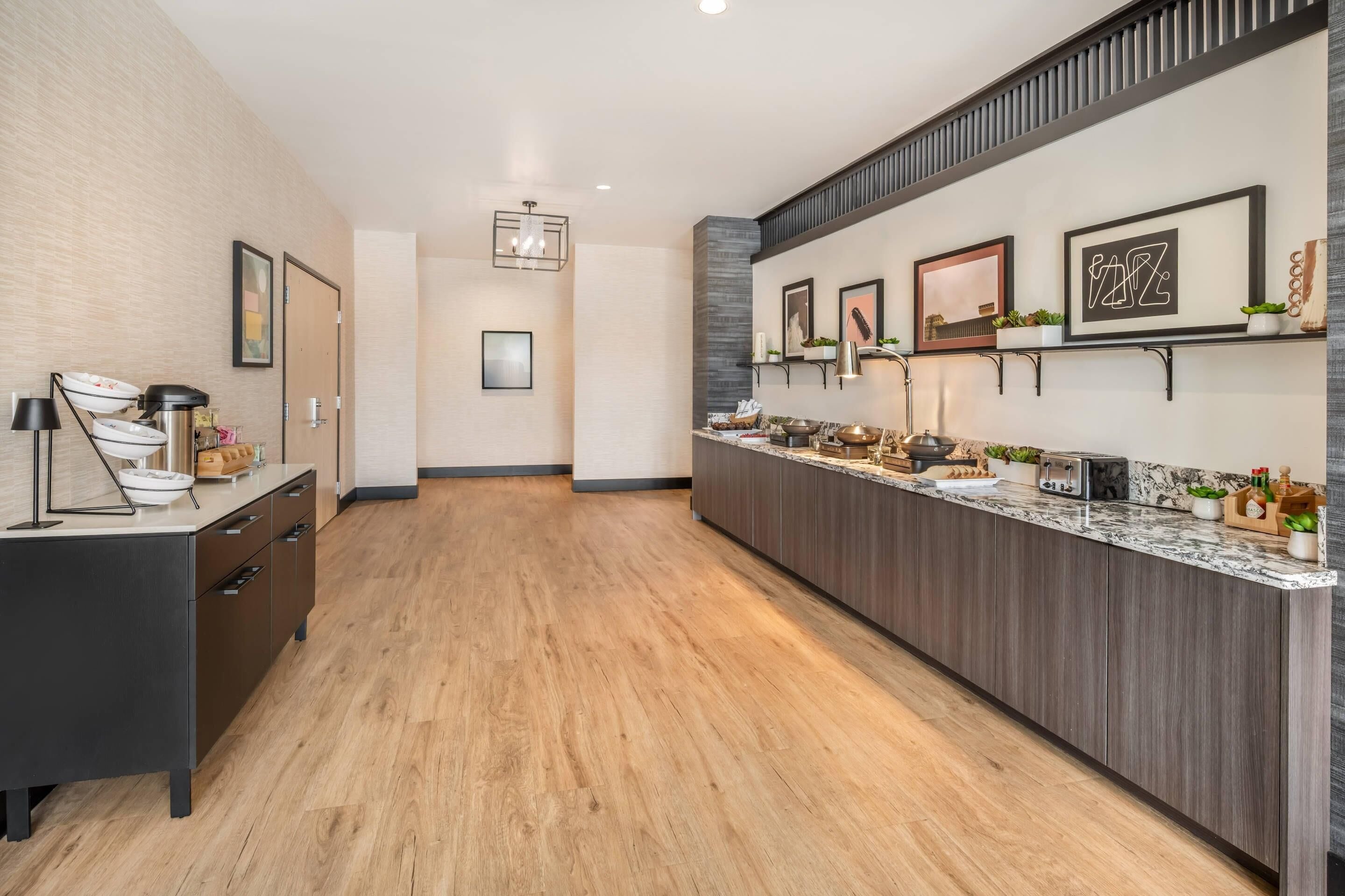 A modern kitchen with a long countertop, wooden cabinets, and a variety of kitchen appliances.