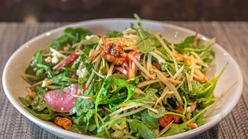 Un tazón de ensalada con diferentes verduras y aderezos.