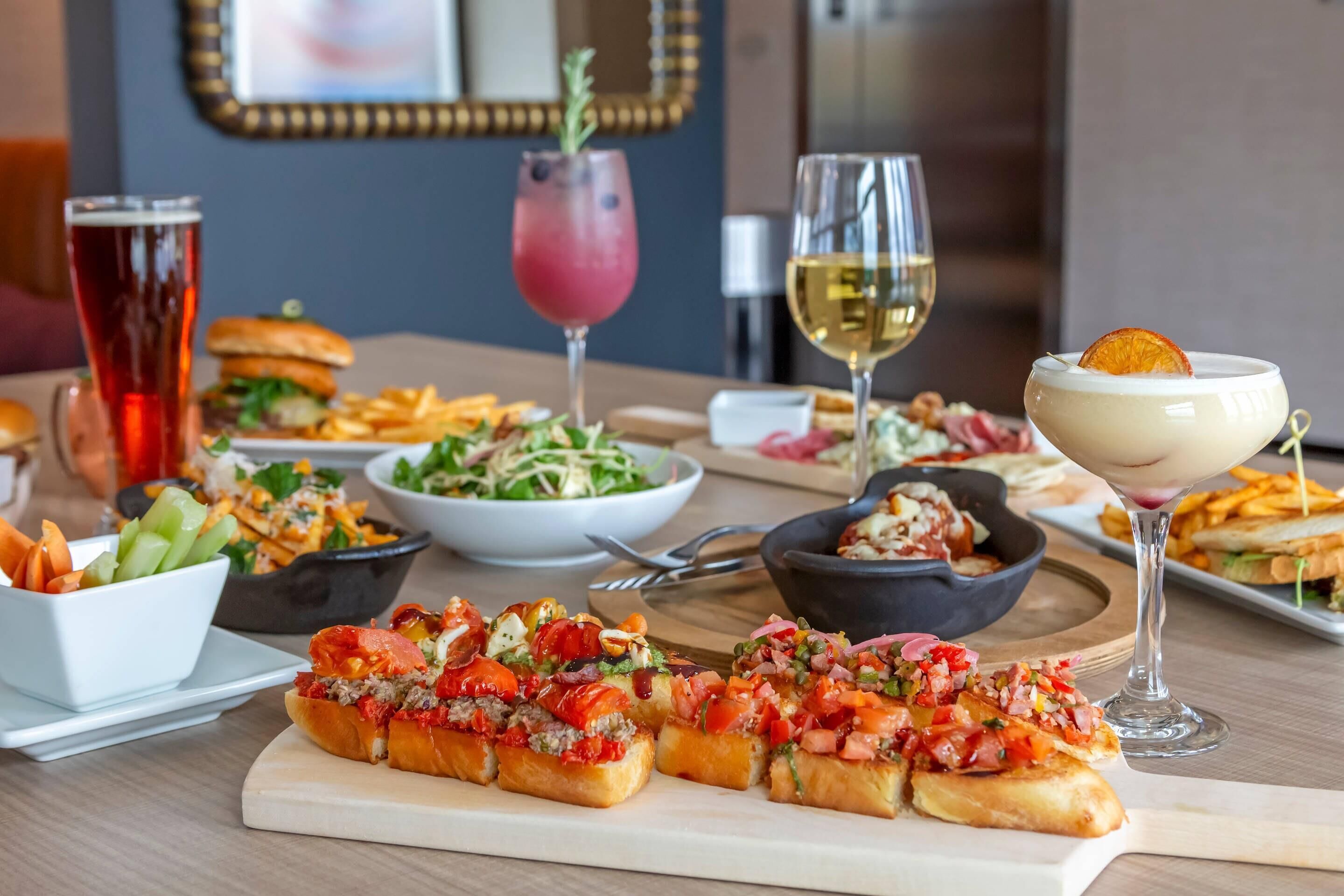A dining table with various dishes, including sandwiches, salads, and drinks.