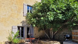 A patio area with a table and chairs, a barbecue grill, and a tree providing shade. - L'alambic à Martial (Menétru-le-Vignoble)