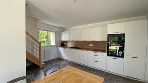 Eine moderne Küche mit weißen Schränken, einer Holz Arbeitsplatte und einem eingebauten Backofen.