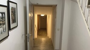 Een hal met een tapijtvloer, een deur die naar een andere kamer leidt, en wanddecoraties.