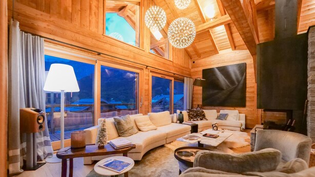 Una sala de estar acogedora con detalles de madera, ventanas amplias, una chimenea y un sofá.