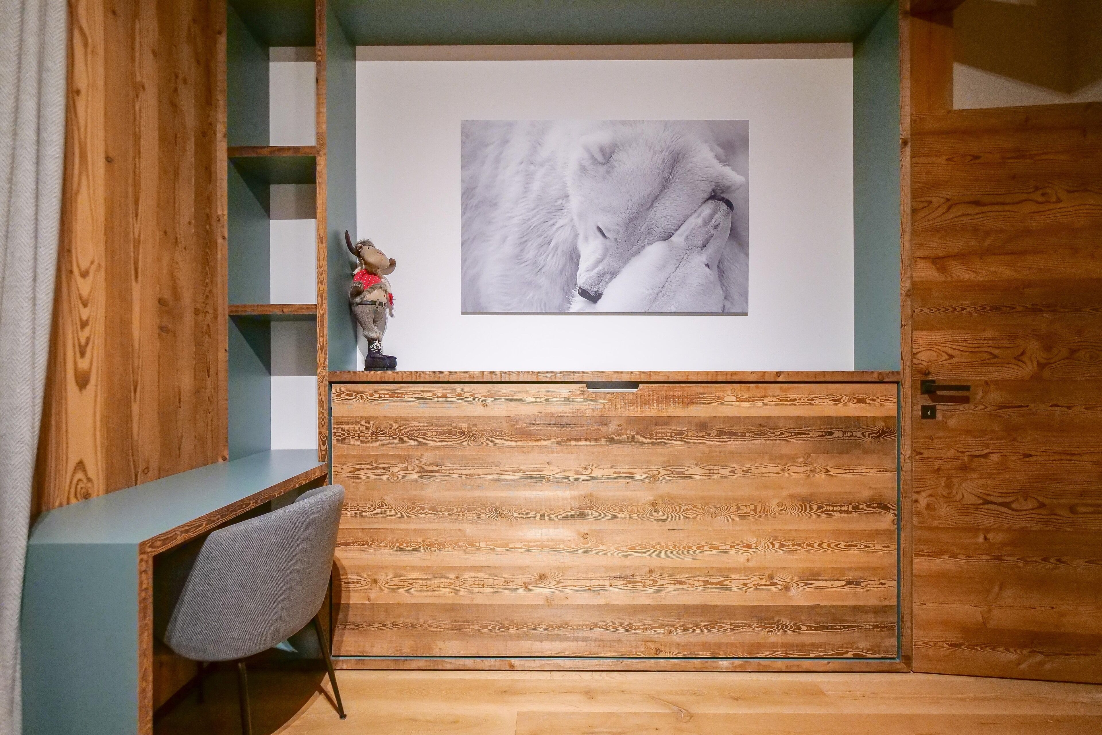 Un bureau en bois avec une chaise, une étagère sur laquelle est posée une figurine, et une photographie encadrée représentant un loup.