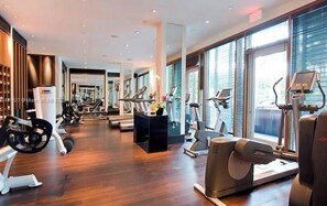 Ein Fitnessstudio mit Cardiogeräten, Gewichten und einer Spiegelwand.