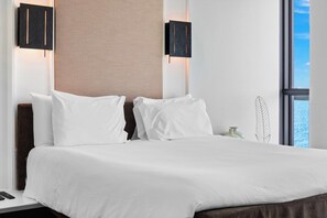 Ein Hotelzimmer mit einem großen Bett, zwei Wandleuchten, einem Fenster mit Aussicht und einer dekorativen Vase.