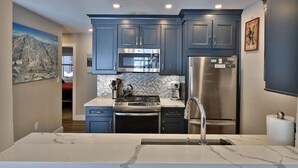 A modern kitchen with grey cabinets, stainless steel appliances, and a marble countertop. - Ski Access from this Kettlebrook Condo with Modern Kitchen (Ludlow)