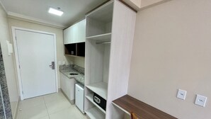 A compact kitchen with a built-in sink, a small refrigerator, and a wooden dining table. - Spazzio diRoma Acqua Park Splash e Slide (Caldas Novas)