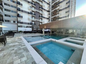 A modern hotel with a rooftop pool area, outdoor seating, and a multi-story building with balconies. - Spazzio diRoma Acqua Park Splash e Slide (Caldas Novas)