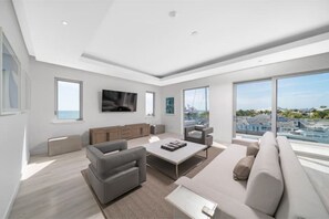 Uma sala de estar moderna com uma janela grande, uma TV de tela plana e um sofá.